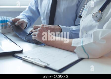In der Nähe der Hände von Patient und Arzt Beratung Behandlung verschreiben. Arbeitet mit x-ray und medizinischen Tests. Stockfoto