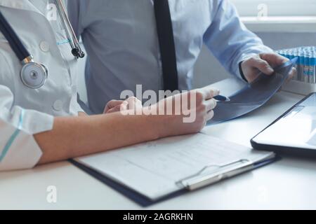In der Nähe der Hände von Patient und Arzt Beratung Behandlung verschreiben. Arbeitet mit x-ray und medizinischen Tests. Stockfoto