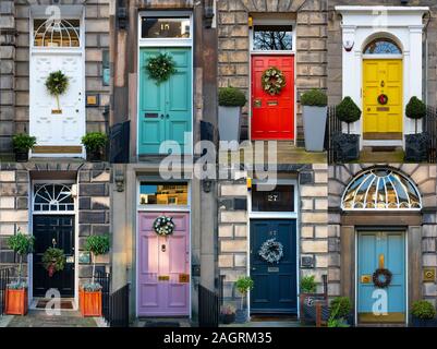 An den farbenfrohen Türen der Stadthäuser in Edinburghs historischer Neustadt sind eine große Auswahl an Weihnachtskränzen befestigt. Schottland, Großbritannien Stockfoto