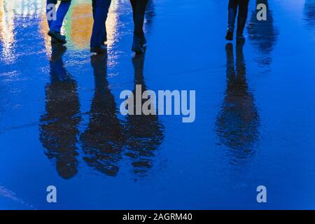 Unscharfe Reflexion Beine und Schatten, Silhouetten der Menschen in den nassen Bürgersteig, in eine Pfütze von Menschen eilten auf einem Regen. Konzept der Jahreszeiten, weath Stockfoto