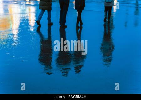 Unscharfe Reflexion Beine und Schatten, Silhouetten der Männer und Frauen in der nassen Bürgersteig, in eine Pfütze, Menschen zu Fuß auf einem Regen. Konzept der Jahreszeiten, w Stockfoto
