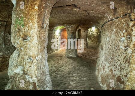 Die unterirdische Stadt Derinkuyu ist eine uralte Höhlenstadt auf mehreren Ebenen in Kappadokien in der Türkei. Stein, der als Tür in der alten U-Bahn-Stadt verwendet wird Stockfoto