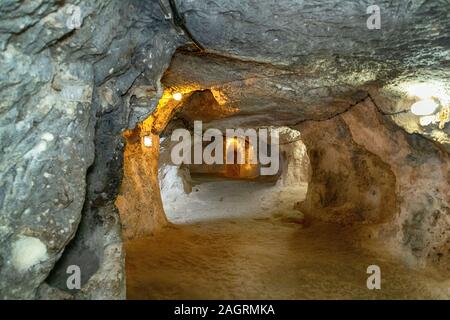 Die unterirdische Stadt Derinkuyu ist eine uralte Höhlenstadt auf mehreren Ebenen in Kappadokien in der Türkei. Stein, der als Tür in der alten U-Bahn-Stadt verwendet wird Stockfoto