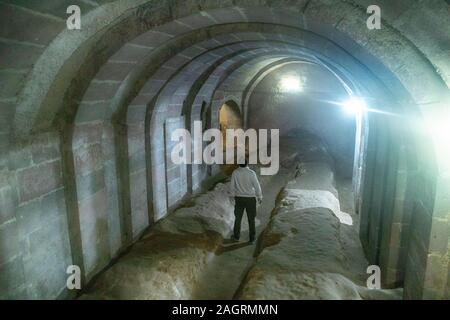 Die unterirdische Stadt Derinkuyu ist eine uralte Höhlenstadt auf mehreren Ebenen in Kappadokien in der Türkei. Stein, der als Tür in der alten U-Bahn-Stadt verwendet wird Stockfoto