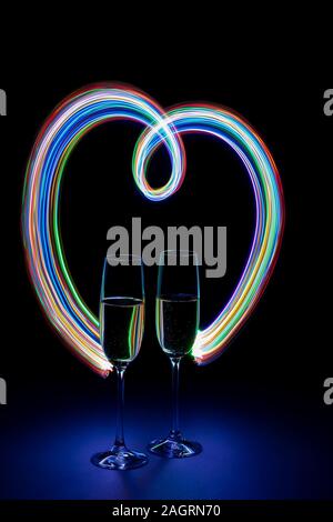 Zwei Gläser Champagner in der Herzförmigen Neon Licht auf dunklem Hintergrund Stockfoto