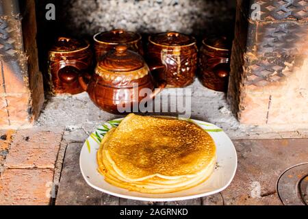 Rosig und heißen Pfannkuchen in einem Russischen Herd gekocht. Maslenitsa - Winter Ade. Stockfoto