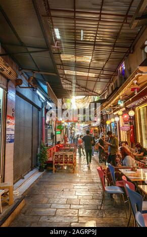 Historischer Kemeralti Markt in Izmir, Türkei. Menschen, die durch den Markt gehen und im traditionellen türkischen Café im historischen Basar sitzen Stockfoto