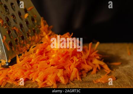 Geriebenen rohen Karotten close-up. Ein Haufen von gehackte Karotten vor dem Kochen. Zutat für das Kochen. Augenhöhe schießen. Selektive konzentrieren. Stockfoto