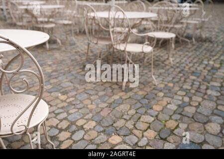 Selektiver Fokus auf Metall Stühle und Tische auf einer gepflasterten Terrasse in ein Restaurant im Freien Stockfoto