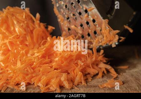 Ein Bündel von geraspelten Möhren. Eine Menge manuell gehackte Wurzel Gemüse auf den Tisch. Close-up. Augenhöhe schießen. Selektive konzentrieren. Stockfoto