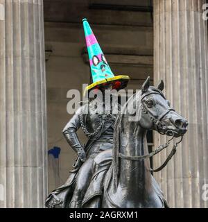 Glasgow, UK. 21. Dezember 2019. Am letzten Samstag vor Weihnachten einkaufen, Tausende von Kunden in Scharen in das Stadtzentrum von Glasgow auf die Straße Unterhaltung durch Govan Zweig der Heilsarmee, die internationale Lebensmittel auf den Märkten und die vielen executive Geschäfte in der Buchanan Street, Glasgow's tyle Meile" bekannt. Hier die Statue des Herzogs von Wellington hat die traditionelle respektlos Parkplatz Kegel mit einem in festlichen Farben ersetzt hatte. Credit: Findlay/Alamy Nachrichten Stockfoto