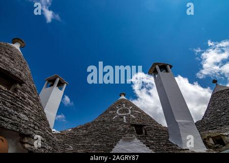 Dächer von truli, typisch weiß getünchten zylindrische Häuser in Alberobello, Apulien, Italien mit tollen blauen Himmel mit Wolken und Sonne Stockfoto