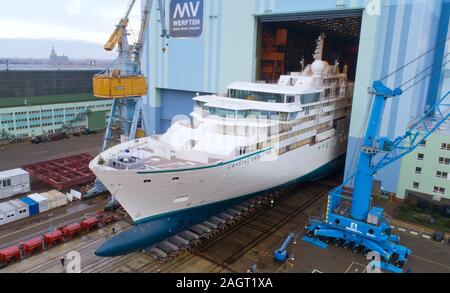 Stralsund, Deutschland. 21 Dez, 2019. Der erste Neubau auf der Werft in Stralsund MV für die genting Group hat die Schiffbauhalle links und steht auf dem Schiff heben (Luftbild mit Drone). Es ist der erste von zwei Eisklettern expedition Kreuzfahrt Schiffe der Klasse der "Crystal". Es war im August 2018 auf Kiel gelegt. Nach Angaben der Werft, das 164 Meter lange Schiff für bis zu 200 Passagiere ist gleichermaßen geeignet für polar Regionen und tropischen Gewässern. Es soll im Frühjahr 2020 fertig sein. Quelle: Stefan Sauer/dpa-Zentralbild/dpa/Alamy leben Nachrichten Stockfoto