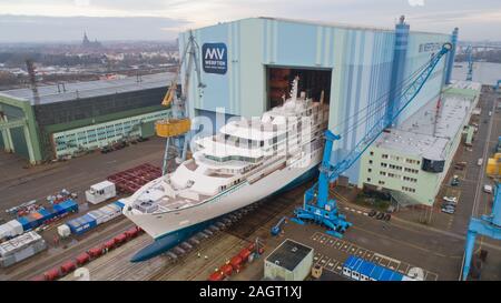 Stralsund, Deutschland. 21 Dez, 2019. Der erste Neubau auf der Werft in Stralsund MV für die genting Group hat die Schiffbauhalle links und steht auf dem Schiff heben (Luftbild mit Drone). Es ist der erste von zwei Eisklettern expedition Kreuzfahrt Schiffe der Klasse der "Crystal". Es war im August 2018 auf Kiel gelegt. Nach Angaben der Werft, das 164 Meter lange Schiff für bis zu 200 Passagiere ist gleichermaßen geeignet für polar Regionen und tropischen Gewässern. Es soll im Frühjahr 2020 fertig sein. Quelle: Stefan Sauer/dpa-Zentralbild/dpa/Alamy leben Nachrichten Stockfoto