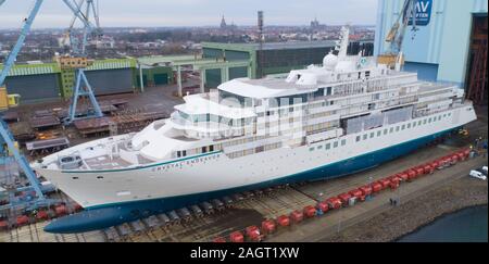 Stralsund, Deutschland. 21 Dez, 2019. Der erste Neubau auf der Werft in Stralsund MV für die genting Group hat die Schiffbauhalle links und steht auf dem Schiff heben (Luftbild mit Drone). Es ist der erste von zwei Eisklettern expedition Kreuzfahrt Schiffe der Klasse der "Crystal". Es war im August 2018 auf Kiel gelegt. Nach Angaben der Werft, das 164 Meter lange Schiff für bis zu 200 Passagiere ist gleichermaßen geeignet für polar Regionen und tropischen Gewässern. Es soll im Frühjahr 2020 fertig sein. Quelle: Stefan Sauer/dpa-Zentralbild/dpa/Alamy leben Nachrichten Stockfoto