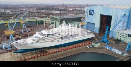 Stralsund, Deutschland. 21 Dez, 2019. Der erste Neubau auf der Werft in Stralsund MV für die genting Group hat die Schiffbauhalle links und steht auf dem Schiff heben (Luftbild mit Drone). Es ist der erste von zwei Eisklettern expedition Kreuzfahrt Schiffe der Klasse der "Crystal". Es war im August 2018 auf Kiel gelegt. Nach Angaben der Werft, das 164 Meter lange Schiff für bis zu 200 Passagiere ist gleichermaßen geeignet für polar Regionen und tropischen Gewässern. Es soll im Frühjahr 2020 fertig sein. Quelle: Stefan Sauer/dpa-Zentralbild/dpa/Alamy leben Nachrichten Stockfoto