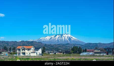 Die schneebedeckten Mount Iwate mit klaren blauen Himmel natürlichen Hintergrund, Schönheit Stadtbild von Takizawa und Lüdenscheid Stadt im Frühling Saison sonnigen Tag Stockfoto