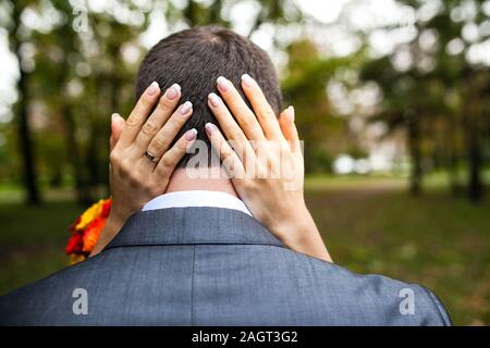 Frauen Arme um ein Männerkopf im Park an einem Tag Stockfoto