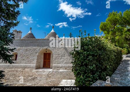 Dächer und Eingang von truli, typisch weiß getünchten zylindrische Häuser in Alberobello, Apulien, Italien mit tollen blauen Himmel mit Wolken, Street View Stockfoto