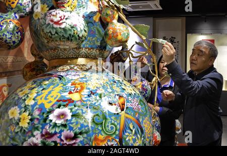 (191221) - Peking, 21. Dez., 2019 (Xinhua) - Artist Zhong Liansheng führt ein Stück von riesigen cloisonne Kunstwerke konzipiert und von ihm produziert in Peking, der Hauptstadt von China, Dez. 12, 2019. Cloisonne, eine Weltweit bekannte traditionelle Handwerkskunst von Peking, wurde als nationale immateriellen Kulturerbes im Jahr 2006 aufgeführt. Die Herstellung von Cloisonne integriert viele professionelle Techniken wie bildende Kunst, Carving, Inlay, Glas schmelzen und Metallurgie und so weiter, die unverwechselbaren chinesischen Stil und tief greifenden kulturellen Konnotation. Peking Emaille Factory Co., Ltd., 1956 gegründet, ist Stockfoto