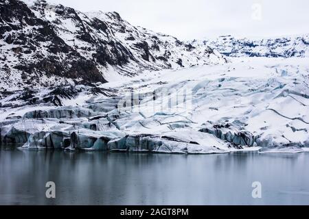 Faszinierende Landschaft des zerklüfteten Hügels und des gefrorenen Sees Im Winter Stockfoto