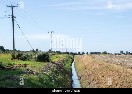 Ein kleiner Bach, der an der Seite der offenen Felder läuft, in der Britischen Landschaft. Stockfoto