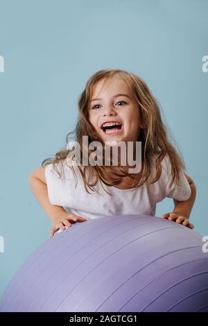 Blue-Eyed Girl spielt mit violett fintes Ball. Stockfoto