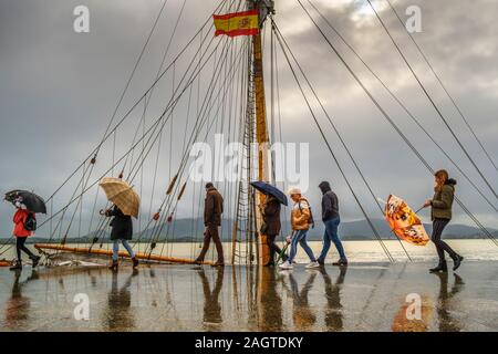 Leute, die an einem regnerischen Tag entlang der Strandpromenade Muelle Calderon, Paseo de Pereda. Kantabrischen Meer Santander. Kantabrien, Spanien. Europa Stockfoto