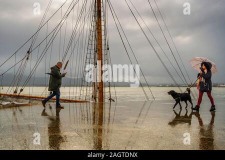 Leute, die an einem regnerischen Tag entlang der Strandpromenade Muelle Calderon, Paseo de Pereda. Kantabrischen Meer Santander. Kantabrien, Spanien. Europa Stockfoto