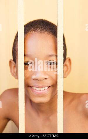 Schönen kubanischen Jungen hinter einem gelben Zaun, Santiago de Cuba Stockfoto