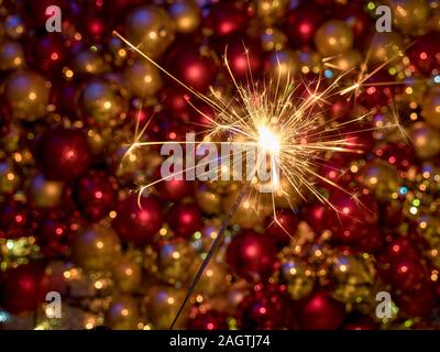 Close up Wunderkerzen Feuerwerk leuchtet vor ein tolles neues Jahr Dekoration mit gold Rot Gelb dekorative Kugeln Stockfoto