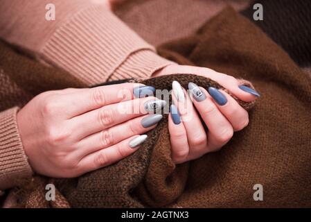 Nagellack. Kunst Maniküre. Moderner Stil Nagellack. elegante Pastellfarben pink Nägel halten wolle Material sleeve Bluse. Stockfoto