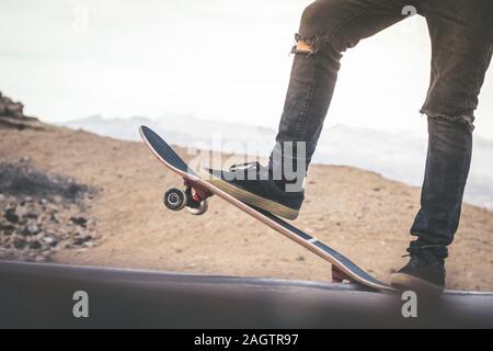 Nahaufnahme der jugendlich Füße auf einem Skateboard bereit, eine Fahrt über die Halfpipe zu starten. Skater starten Sprünge und Tricks an der Skate Park. Lassen Sie uns en gehen Stockfoto