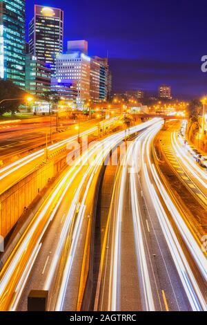 Verschwommen Hedlights der vorbeifahrenden Autos fahren auf der Autobahn in der Nähe von North Sydney Warringah high-rise office Towers bei Sonnenuntergang von Overhead Road Bridge. Stockfoto