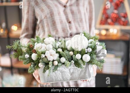 Anordnung der frischen Fichten in einem Metall Topf in womans Hände. Europäische Blumen Shop. Weihnachtliche Stimmung. Stockfoto