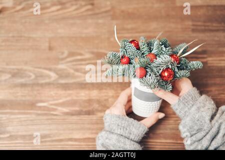 Schöne festliche Anordnung von frischen Fichten in der Kaffeetasse. Weihnachtliche Stimmung. Holztisch Stockfoto