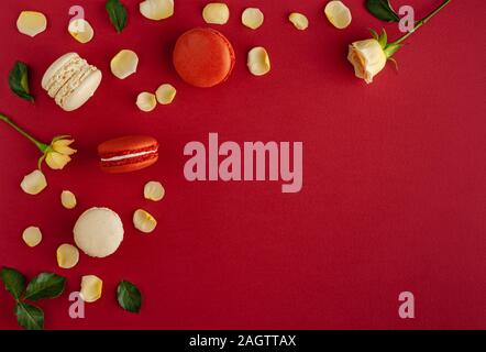Roter Hintergrund mit Rosen, Blüten und macarons. Flach, kopieren. Grußkarte Konzept Stockfoto