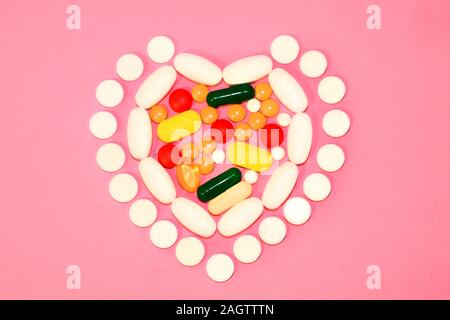 Die Pillen sind in der Form eines Herzens. Auf einem rosa Hintergrund. Ansicht von oben. Platz für Text. Stockfoto