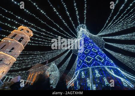 Geschmückten Weihnachtsbaum in Vilnius Cathedral Square bei Nacht. Auf der linken Seite - der Glockenturm, dahinter - die Kathedrale. Eine Masse von Menschen zu Weihnachten Stockfoto