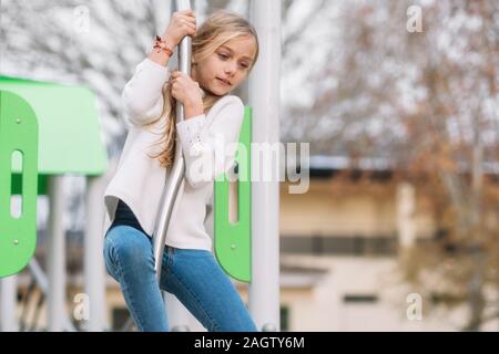 Hübsches, kleines Mädchen spielen auf Kinder spielplatz, bereit durch Pol zu schieben. Stockfoto