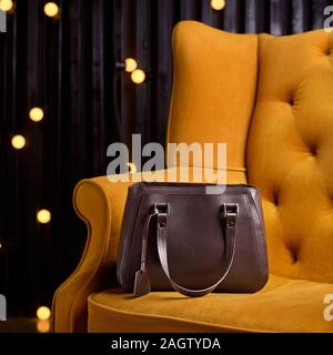 Braun Leder Tasche für Business Woman, auf der gelben Sessel. 1:1 Kopie mit Platz für Text und Design. Zubehör. Stockfoto