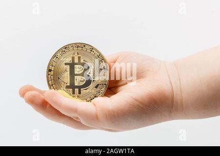 Die Hand des Closeup Kinder in der Handfläche liegt ein bitcoin Münze auf einem weißen Hintergrund. Konzept für Artikel und Beiträge über die Zukunft und Einlagen ich Stockfoto