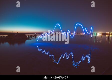 Erstaunlich laser Feuershow Leistung in der Nacht blauer Himmel mit Reflexionen im Meerwasser Stockfoto