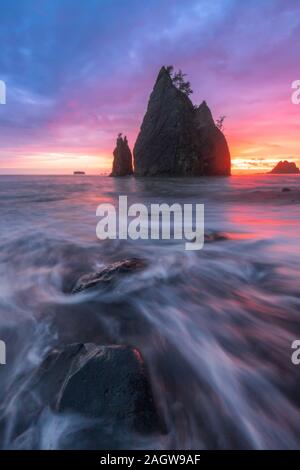 Sonnenuntergang Blick auf Split Rock am Rialto Beach in Olympic National Park mit Wellen von Meer über felsigen Strand hetzen Stockfoto