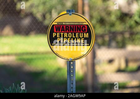 Erdöl pipeline Warnschild mit Maschendrahtzaun und im Hintergrund. Stockfoto