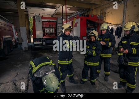 Feuerwehrleute vorbereiten für Notdienst. Die feuerwehrleute setzen auf Handschuhe. Stockfoto