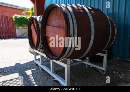 Zwei traditionelle grosse Eiche Holz- Weinfässer auf Metall Unterstützung im Freien neben dem Weingut Gebäude, Okanagan Valley Region, British Columbia, BC, Kanada Stockfoto