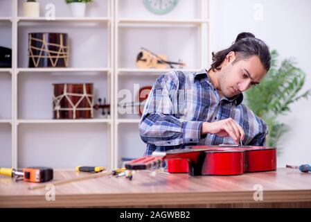 Die junge schöne Handwerker Reparatur Gitarre Stockfoto