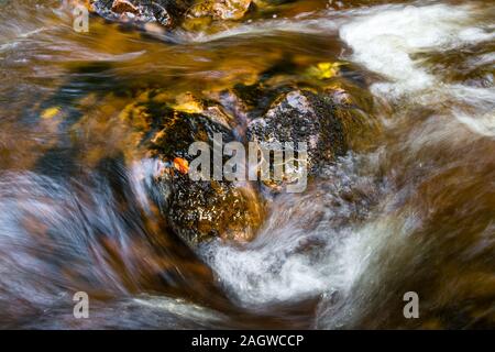 Flache brennen fließt mit frischem Wasser mit einem rötlich-braune Farbe Charakteristisch für das schottische Hochland und die peat Moss, es läuft thru Stockfoto