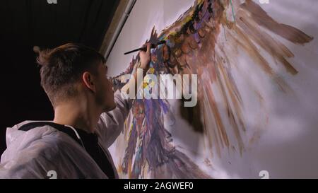 Künstler Designer zieht ein Adler an der Wand. Handwerker Dekorateur malt mit Acryl öl Farbe. Maler Maler gekleidet in Lack auftragen. Indoor. Stockfoto